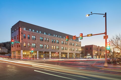 A long exposure shot of a street with a red traffic light and a building in the background.
